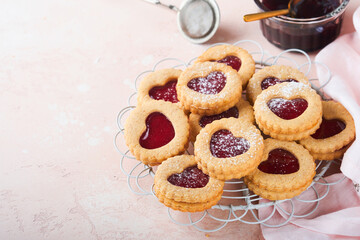 Traditional Linzer cookie with strawberry jam and powder sugar on pink beautiful background. Top view. Traditional homemade Austrian sweet dessert food on Valentines Day. Holiday snack concept.