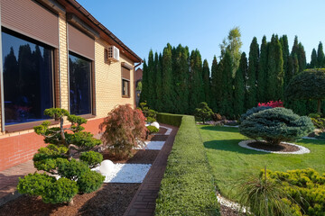 Backyard garden with nicely trimmed bonsai, bushes and stones in front of the European style villa,...