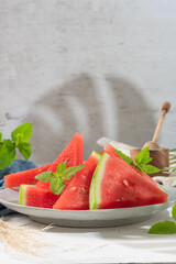 Composition of ripe watermelon and fresh mint on the kitchen table. Ripe summer watermelon. Juicy watermelon. Concept of seasonal fruits on the table