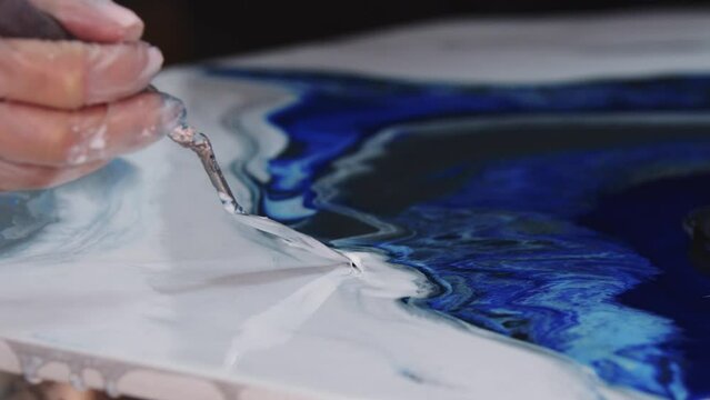 Applying white epoxy on the painting using a spatula