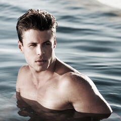 A moment to myself. A handsome male model in water looking to the side.