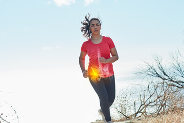 Pushing through the pain. Shot of an attractive young woman running outdoors with her hip injury highlighted. - obrazy, fototapety, plakaty