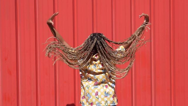 African girl combed with colored braids letting them fall. Typical African hairstyle.