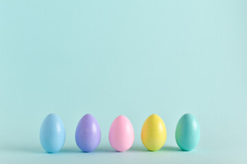 Painted eggs of delicate tones stand on a pale blue background.