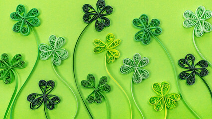 Quilling paper shamrocks leaves on green background. St. Patrick's Day background with clover and trefoil leaves made in paper filigree technique.