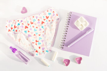 Women's panties underwear, diary with pen, intimate hygiene products, scented candles. Concept of critical days, premenstrual syndrome, abdominal pain, menstruation, women's health, feminine hygiene