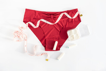 Women's underwear, tampons and metric measuring tape. Concept of premenstrual syndrome, critical days, abdominal pain and bloating. Menstruation, menstrual cycle, women's health, feminine hygiene