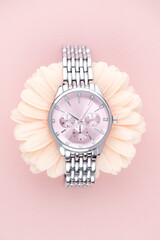 Women's wristwatch with silver metal bracelet and pink dial in the center of the flower on a pink...