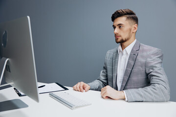 businessmen in a gray suit sits in front of a computer isolated background