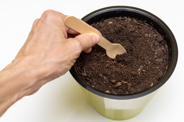 hand tool plows the ground in a flower pot