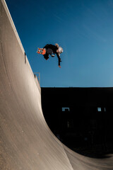 Boy doing backside air on a vert ramp and blue sky