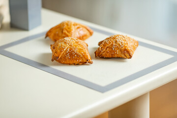 Freshly baked samosa on a baking mat on a home kitchen table.