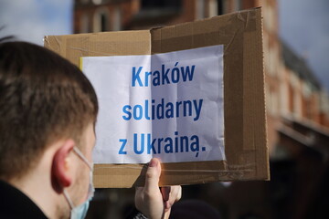 Naklejka na ściany i meble man holding a cardboard box text KRAKOW SOLIDARITY WITH UKRAINE in Polish during public protest