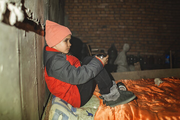 Terrorism and war, current history. Little Ukrainian girl sits in a bomb shelter, drinks tea from a...