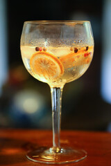 drink de gin com laranja desidratada e sementes servido em uma taça redonda e generosa, capturado durante um vibrante evento