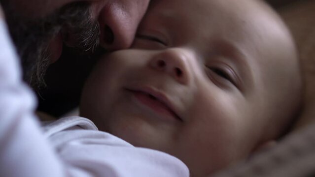 Cinematic exstra close up shot of young bearded Happy neo father is playing kiss with newborn baby son smile in nursery morning. Concept children, parenthood, childhood, life, love, fatherhood, family