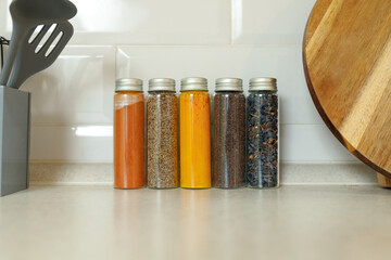 Various spices in jars against the wall on a modern kitchen table with copy space.