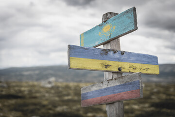 kazahkstan, ukraine and russian flags on signpost outdoors in nature.