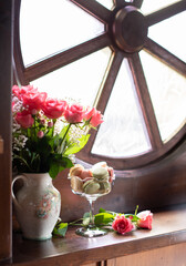 still life on the windowsill, flowers and macaroons, pink roses, colorful candys