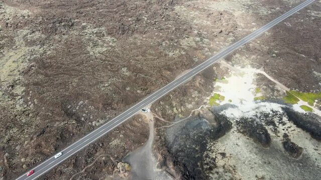 Rocky plain with road and cars on the volcanic island of Lanzarote