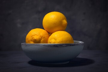 Three lemons in a wooden bowl.