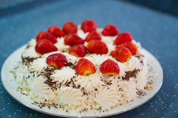 cake decorated with whipped cream and fresh strawberries. homemade dessert.