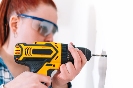 Red-haired woman using a drill at home
