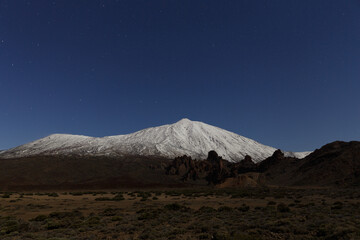 Snow-capped volcano illuminated by moonlight.
