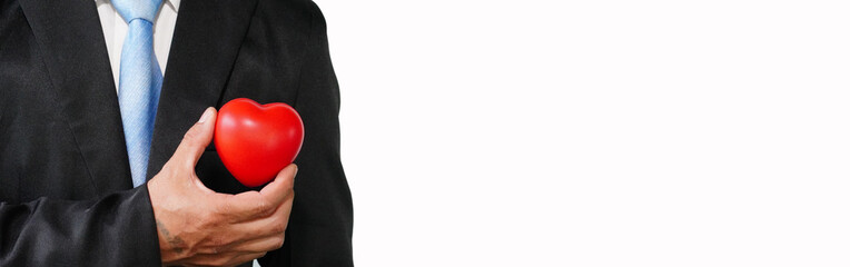 Businessman holding a red heart on his chest in a suit - crm, service business concept with hearts.
on a separate background   