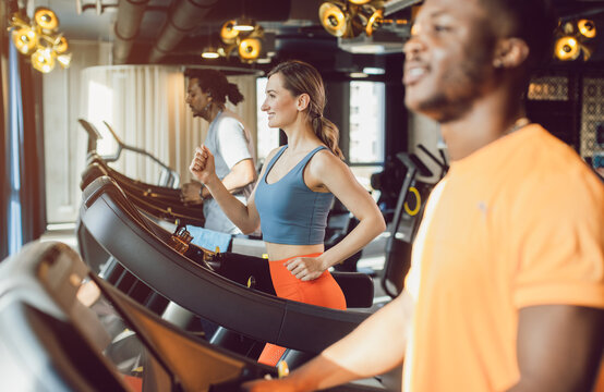 Men and woman, diversity group, in the gym exercising by running on treadmill