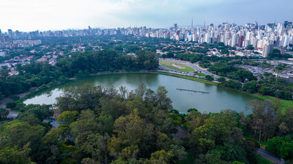 Fototapeta na wymiar Aerial view of Ibirapuera Park in São Paulo, Brazil. Park with preserved green area. Residential and commercial buildings in the background
