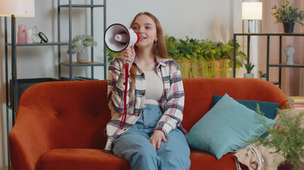 Young woman in casual shirt scream shout in megaphone loudspeaker announces discounts sale of real...