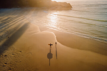 Warm sunrise on ocean with shadow by surfers and waves. Joaquina beach in Brazil