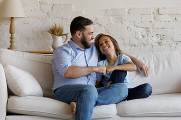 Happy young father his adorable smiling son sit on sofa making fist bump gesture, showing love,...