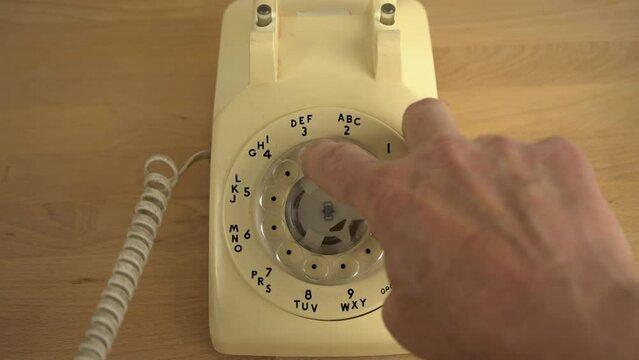 A man dials a number on a vintage rotary phont