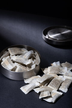 Closeup of metallic Swedish snus can with white portions of smokeless tobacco pouches against a dark background.