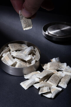 Closeup of metallic Swedish snus can with white portions of smokeless tobacco pouches against a dark background.