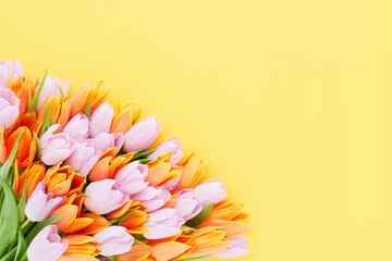 Fototapeta na wymiar Bunch of pink and orange tulips on yellow background. Mothers Day, Valentines Day, birthday concept