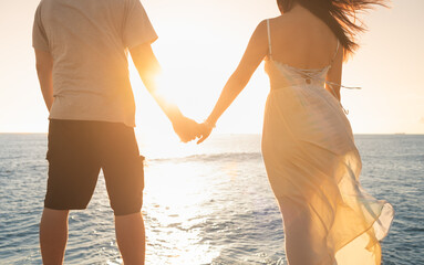 Couple holding hands looking out the a beautiful ocean sunset nature view