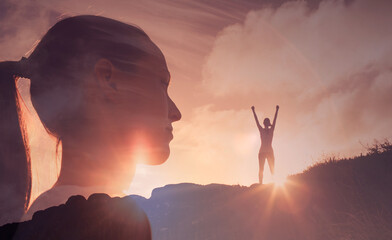Strong confident woman standing on a mountain looking out to the sunrise with fist up to the sky. People, power strength and determination concept 