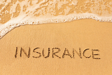 Naklejka na ściany i meble Insurance word symbol written on sandy beach background 