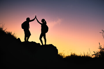 Man and woman hikers giving each other high five. Working in unity, team work, and accomplishing...