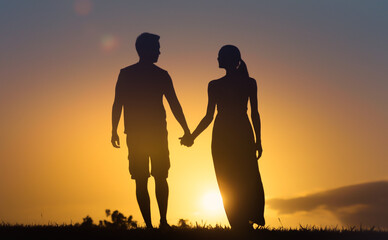 silhouette of couple holding hands walking into the sunset 