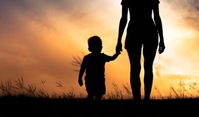 Mother holding her child's hand walking in a meadow 