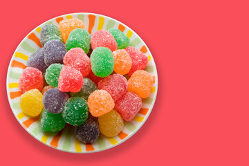 Saucer with colored gummy candies and orange background.