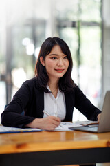 Portrait of Young Asian woman hand freelancer is working her job on computer tablet in modern office. Doing accounting analysis report real estate investment data, Financial and tax systems concept.