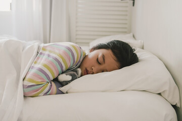 Young mixed race Asian girl sleeping in bed with her soft toy, good night sleep, bedtime routine,...