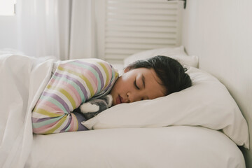 Young mixed race Asian girl sleeping in bed with her soft toy, good night sleep, bedtime routine, wake up kid for school, children sleep disorder, being sick concept