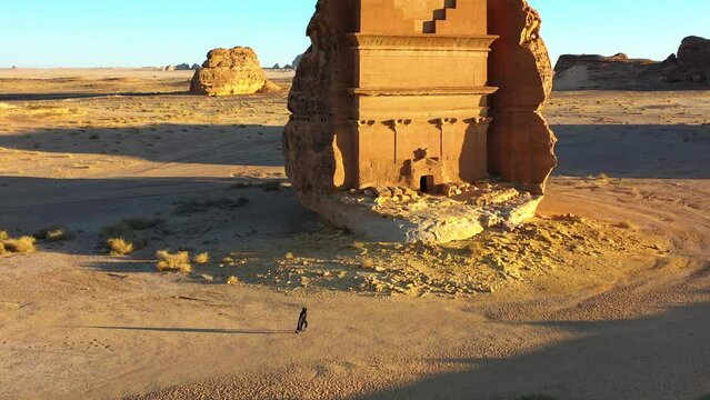 Aerial drone view of a Arab training in front of the Hegra, golden hour in Madain Saleh, Saudi Arabia