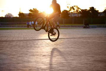 I can make this bmx do whatever I want. Shot of a man doing tricks on his bike, with sun flare.